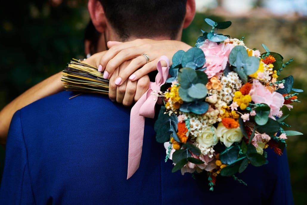 111-JOSE FERREIRO FOTOGRAFIA - FOTOGRAFO DE BODAS EN SANTANDER Detalle del ramo de novia. La foto está tomada por detrás y muestra a la novia abrazando al novio de espaldas ,el ramo lo sujeta con las dos manos por detrás de la espalda del novio.