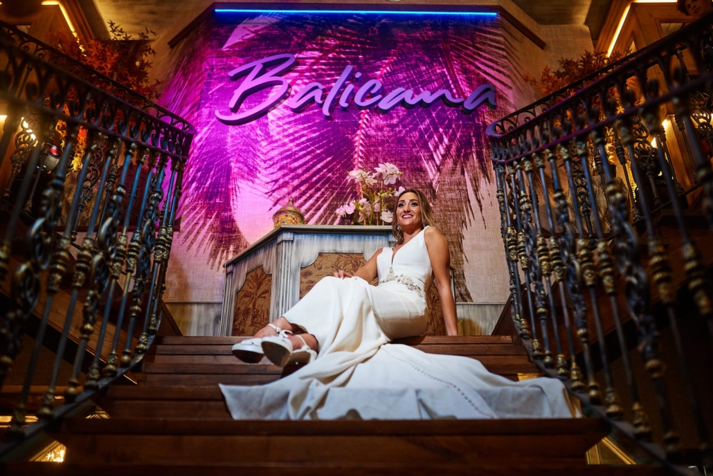 Elegante y guapa novia sentada en las escaleras del Balicana luces para nosotros el día de su postboda