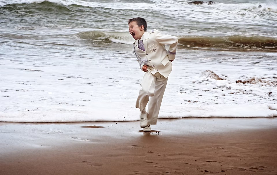 comuniones jose ferreiro 2026-11 Un niño vestido de comunión está jugando con las olas y la arena y corre hacia nosotros