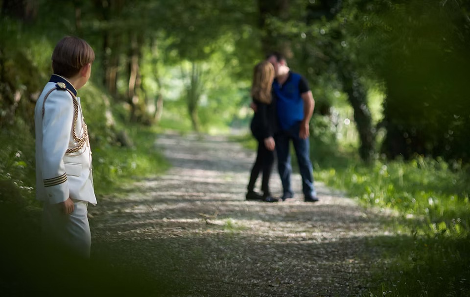 comuniones jose ferreiro 2026-16 Un niño vestido de comunión observa como sus padres al fondo se dan un beso