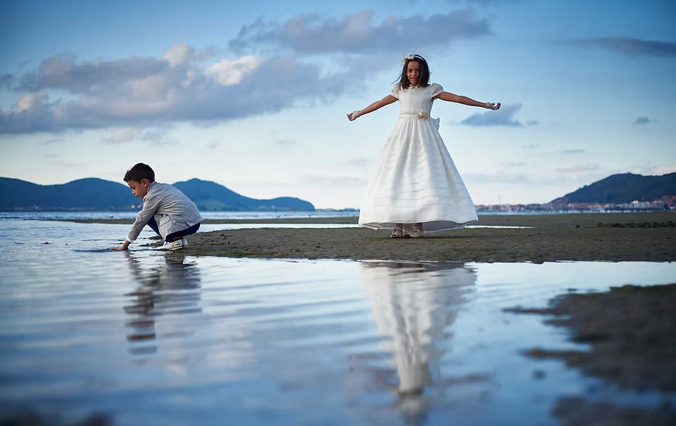comuniones jose ferreiro 2026-19 Una niña vestida de comunión y su hermano están posando en la playa del reggaetón de Laredo juegan con el agua en un entorno precioso