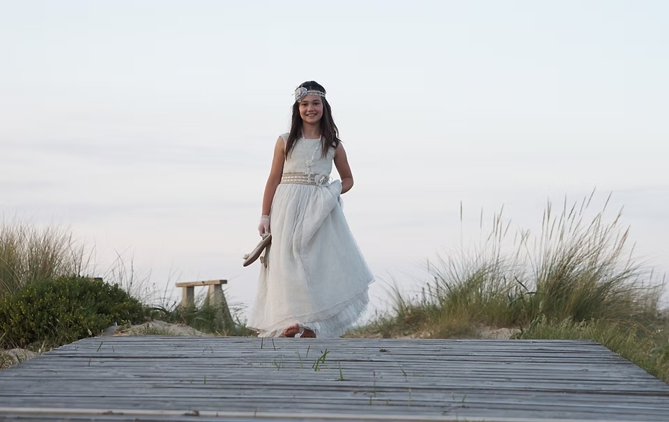 comuniones jose ferreiro 2026-3 Fotografía de una niña vestida de comunión en una pasarela de madera en las dunas de berria