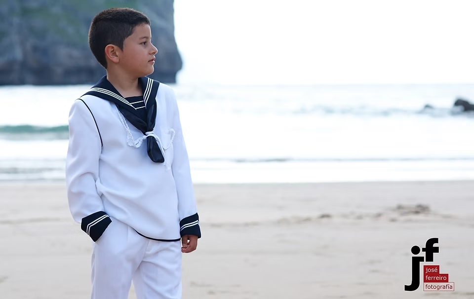comuniones jose ferreiro 2026-4 Fotografía de un niño vestido de comunión en una playa el niño va a vestido de marinero
