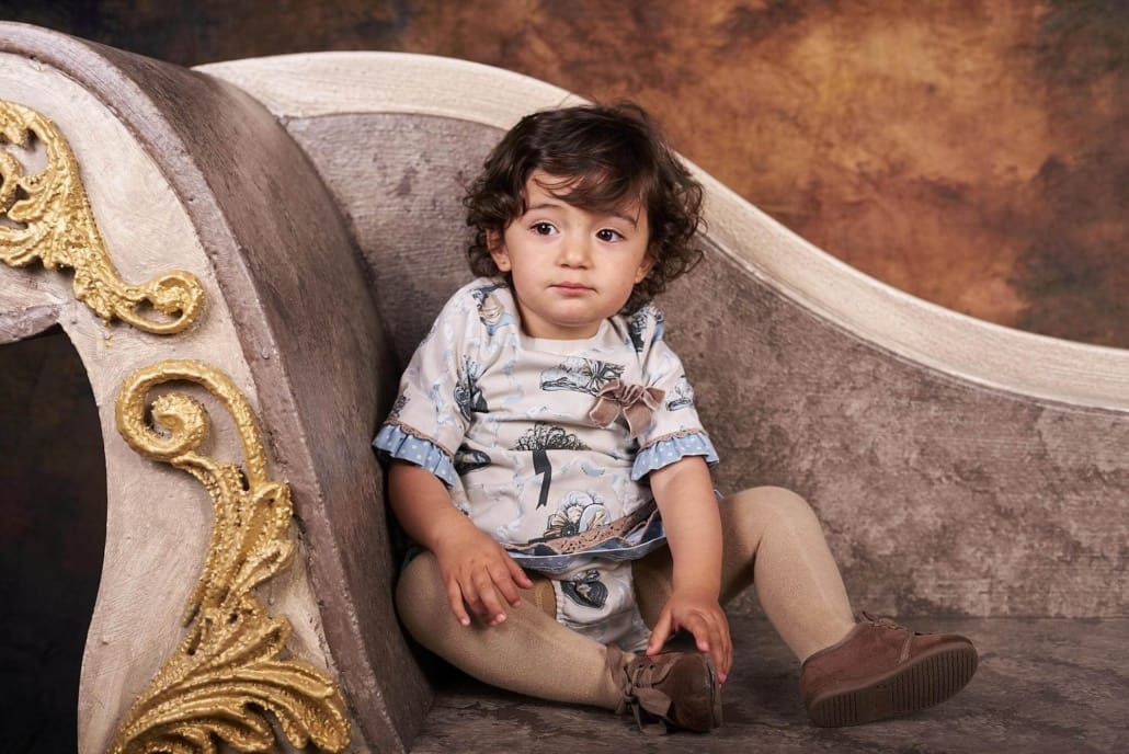 foto infantil de estudio, la niña está sentada en nuestro divan, en el estudio