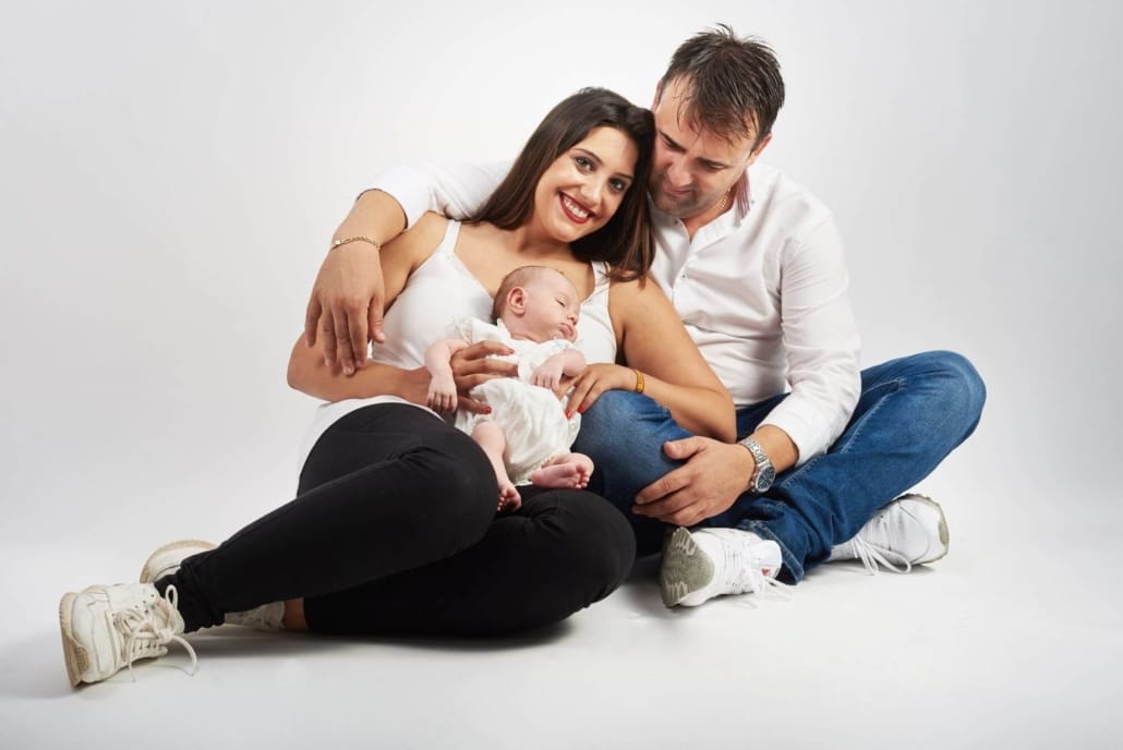 una foto familiar de una pareja con su hijo en el estudio, sentados en un fondo blanco