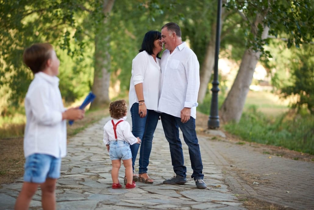fotografia de familia en exteriores, los padres se besan mientras sus hijos les miran