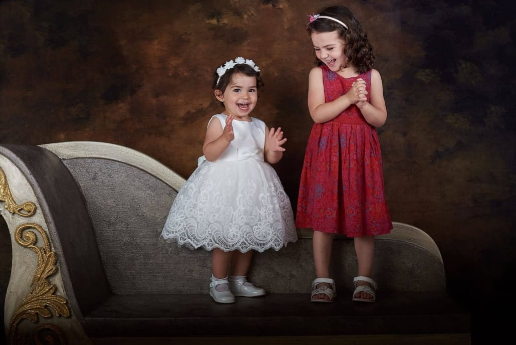 foto infantil de unas niñas , estan posando , de pie, en nuestro divan